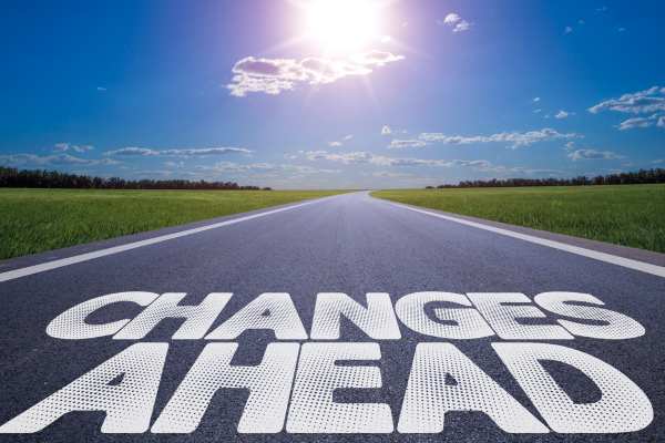 The words Changes Ahead on a highway surrounded by green grass and a blue sunny sky