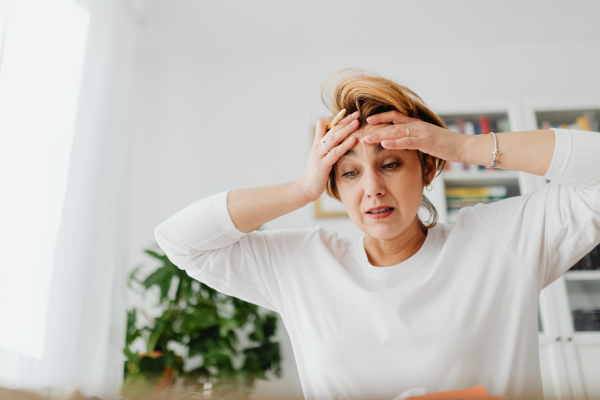 Woman holding her head and looking stressed out from worrying about everything.