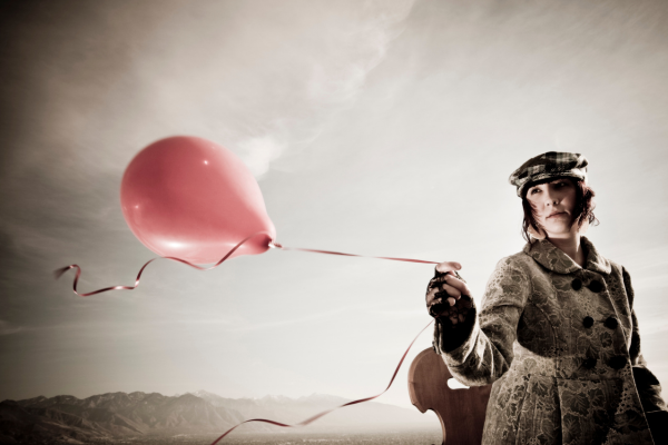 Image of woman holding a pink balloon and thinking of why she is struggling to let it and other things go.