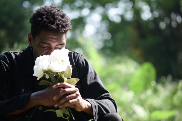grief therapy - man in black shirt smelling white roses